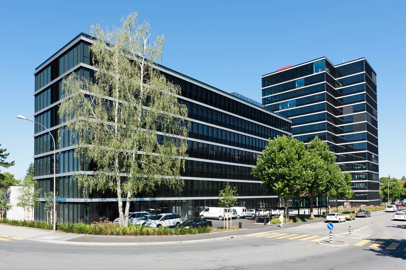 Swissinfo headquarters building, a modern black and glass structure, under a clear blue sky.