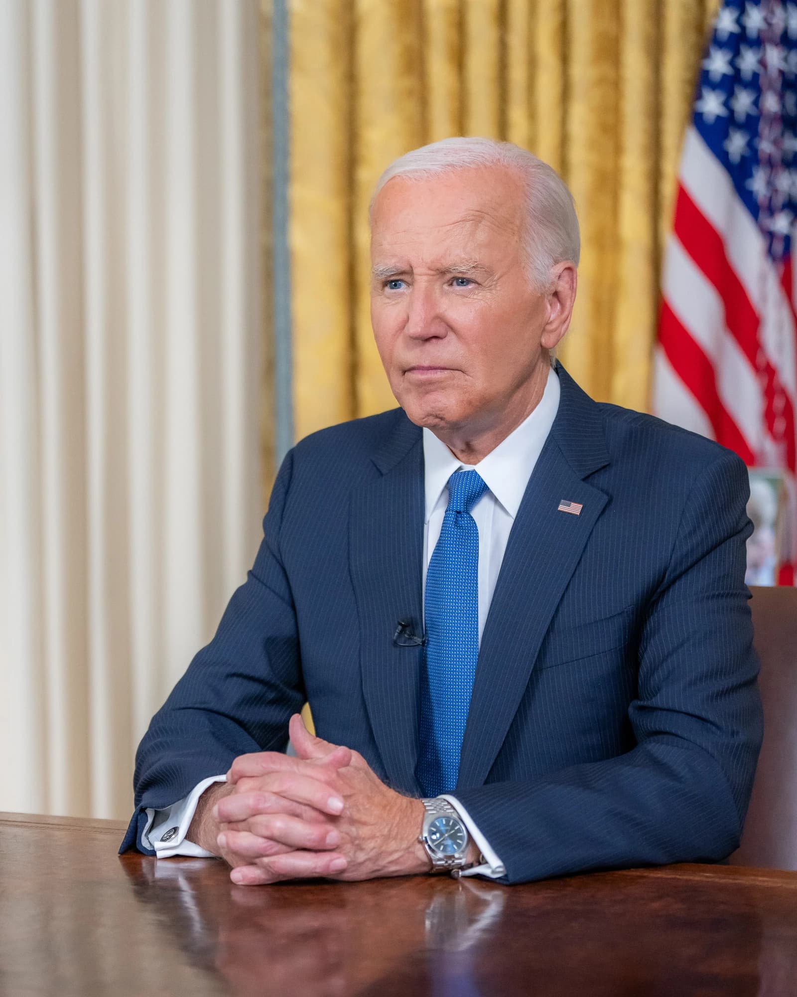 President Joe Biden sits at a desk in the Oval Office.