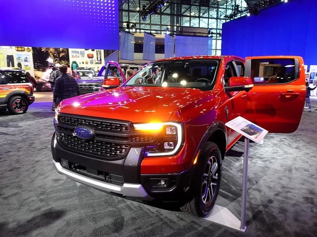 A red 2024 Ford Ranger Lariat 4WD SuperCrew pickup truck displayed indoors.