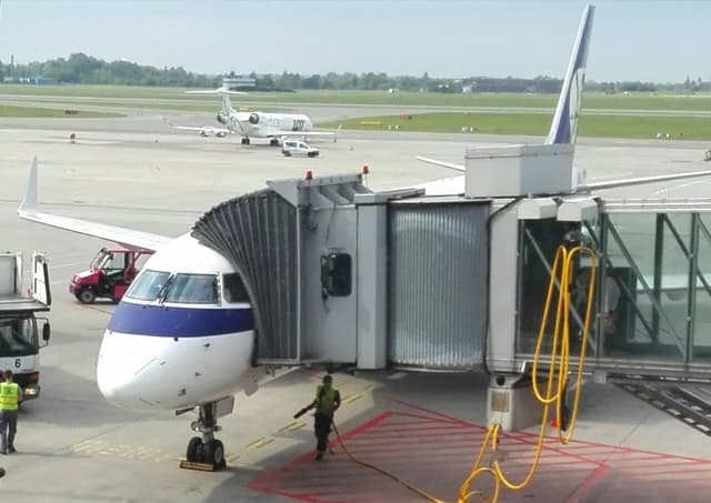 Embraer 195 airplane docked at a passenger gate at an airport.