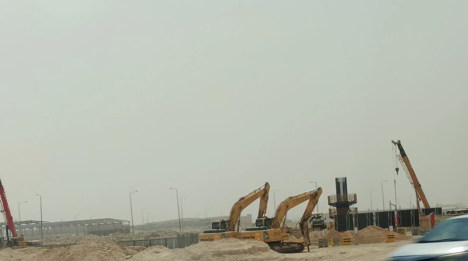 Construction equipment and ongoing building work at a large industrial site in Riyadh.