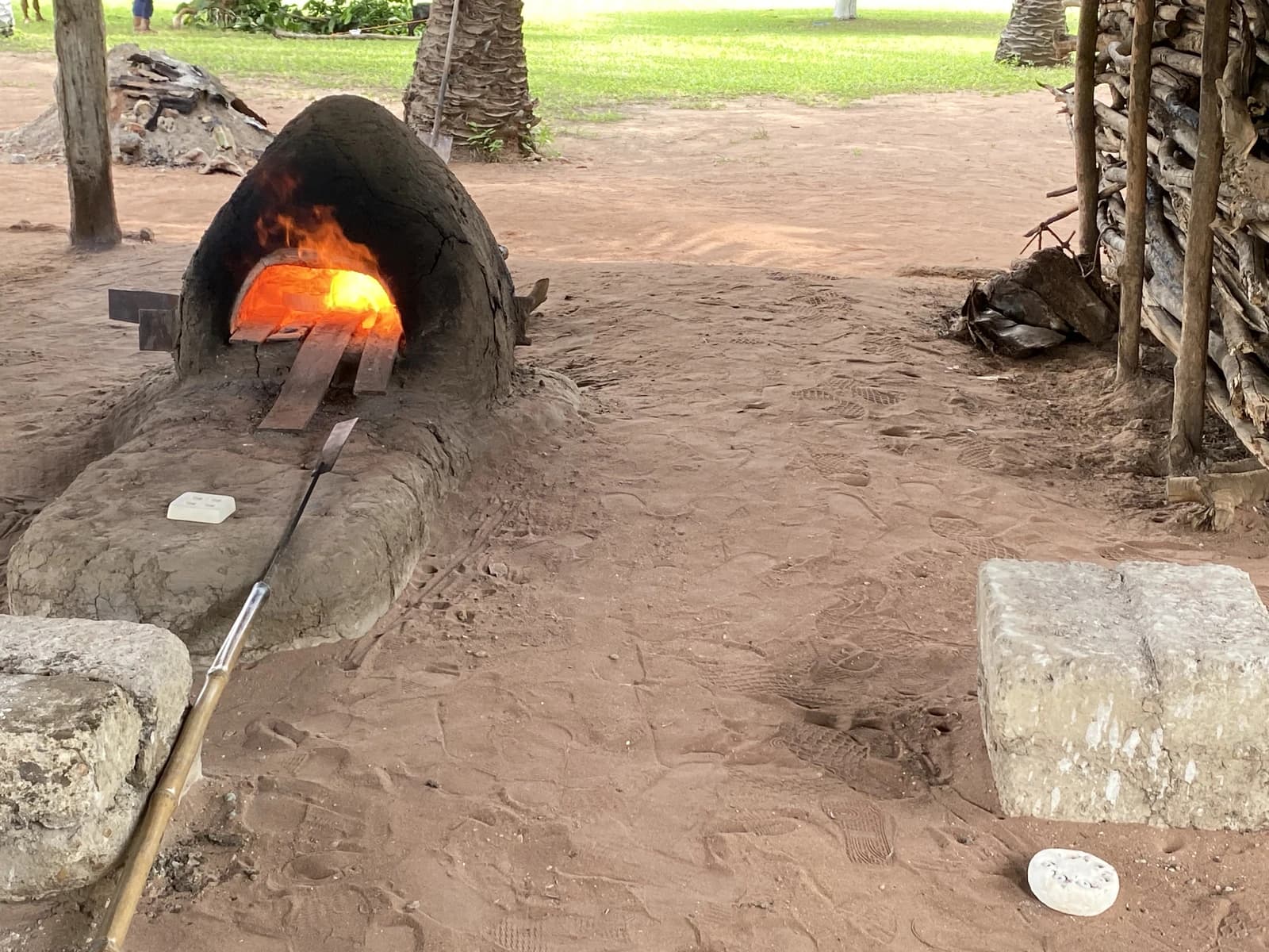 An outdoor clay kiln melting glass at high temperatures, with visible flames.