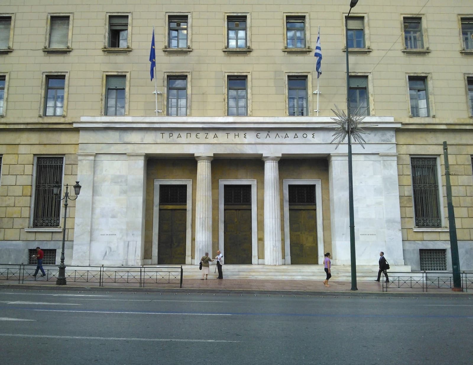 Main entrance to the Bank of Greece central building with columns and Greek text.