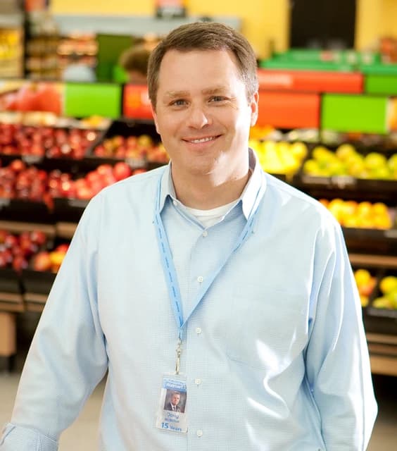 Doug McMillon, CEO of Walmart, standing in a grocery store aisle.