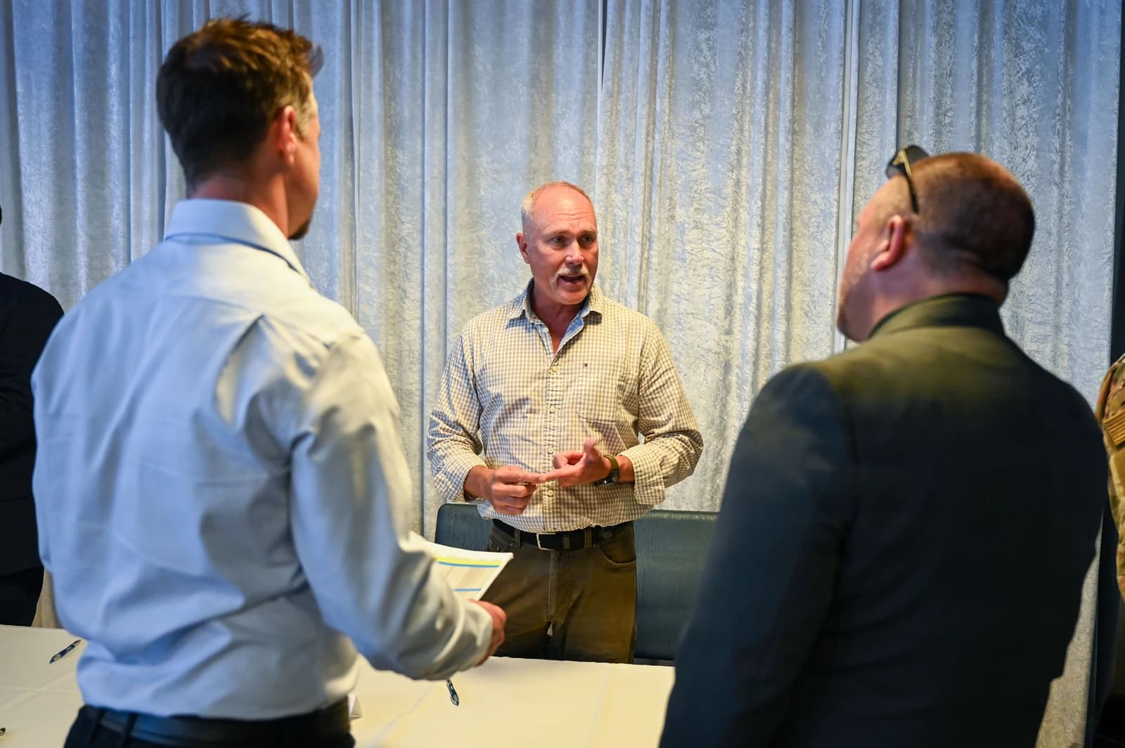 Man with a mustache speaks to two other people at a career fair.