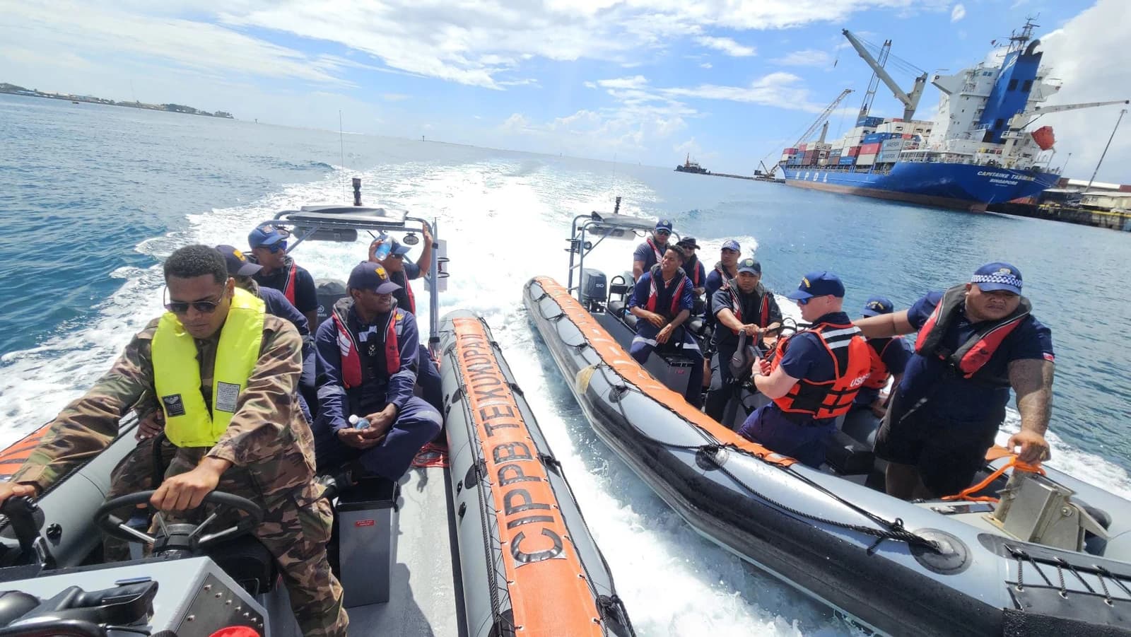 Coast Guard personnel and partners on two patrol boats in ocean waters.