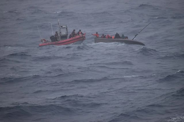 U.S. Coast Guard crew on a rescue boat assisting people in a sinking vessel.