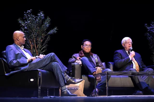 Robert Kiyosaki, Radha Gopalan, and Dennis Prager seated and speaking with microphones.