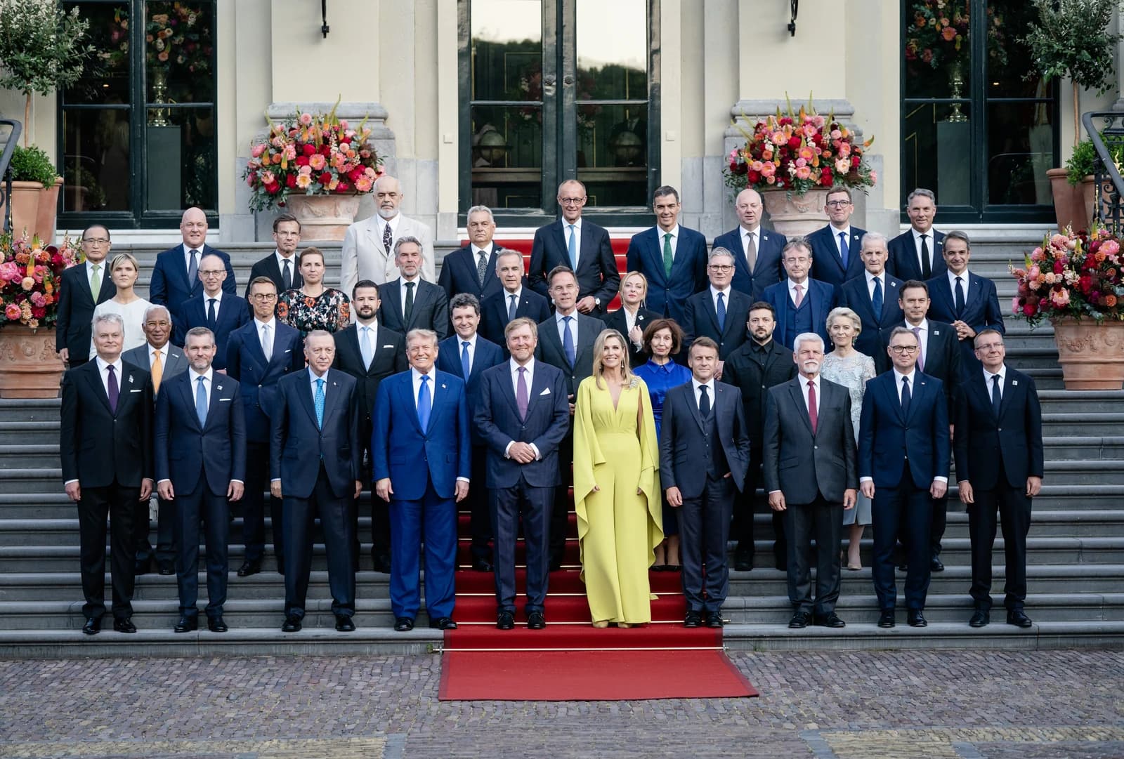 A large group of heads of state and government posed for a formal portrait on stairs.