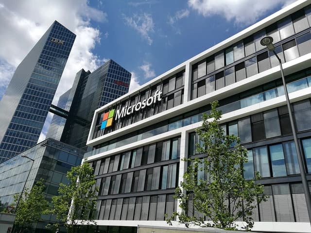Microsoft Germany Headquarters building with its logo on the facade and other skyscrapers.