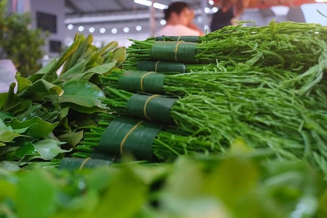 Bundles of fresh, green leafy vegetables displayed for sale at a market stall.