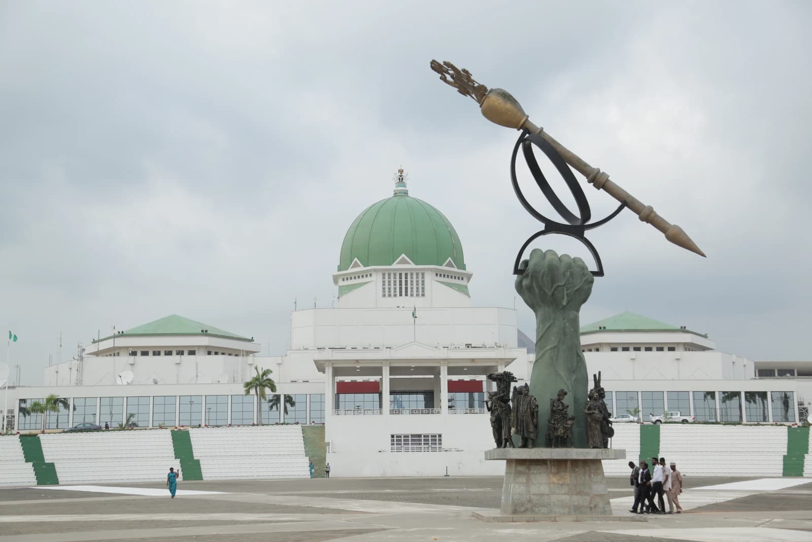 Exterior view of the National Assembly Building in Abuja, Nigeria, under a cloudy sky.