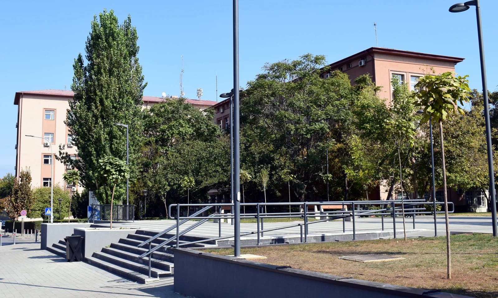 Exterior of the Prishtina Municipality Building with trees and a public plaza.