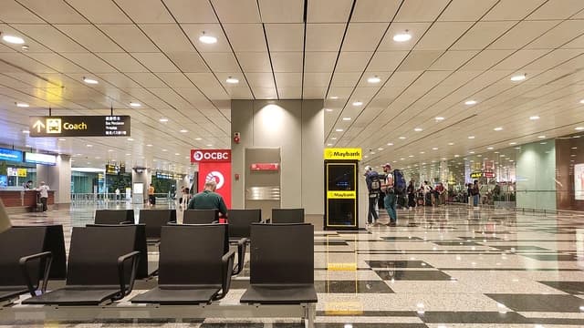 Interior of Singapore Changi Airport Terminal 4 with waiting area and passengers.