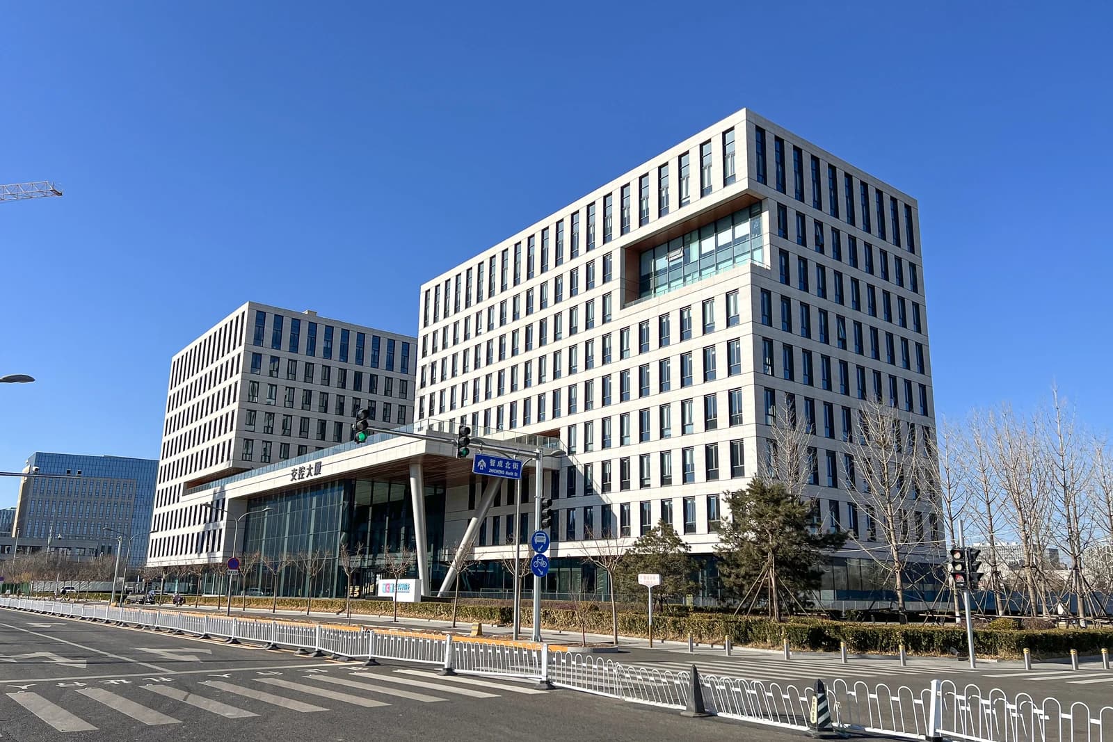 Modern multi-story office buildings with a street and traffic lights in the foreground.