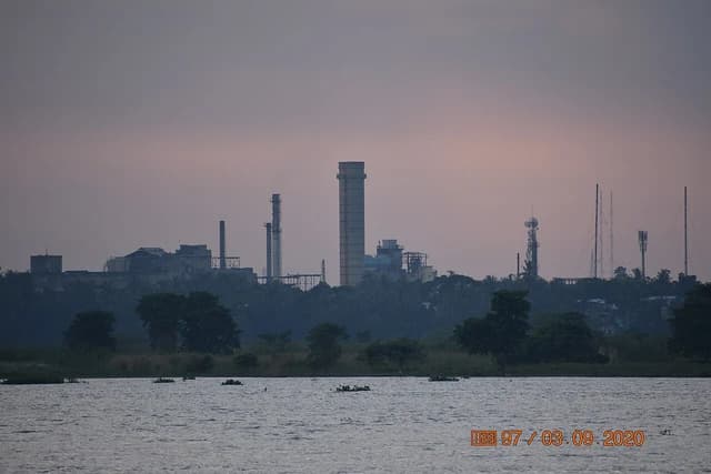 Bandel Thermal Power Station and smoke stacks across a body of water at dusk.