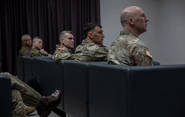 Military personnel, including a US Army soldier, attending a forum or briefing.