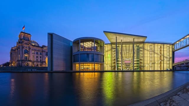 Reichstag Building and Paul-Löbe-Haus, German parliamentary buildings, seen across the Spree River at dusk.