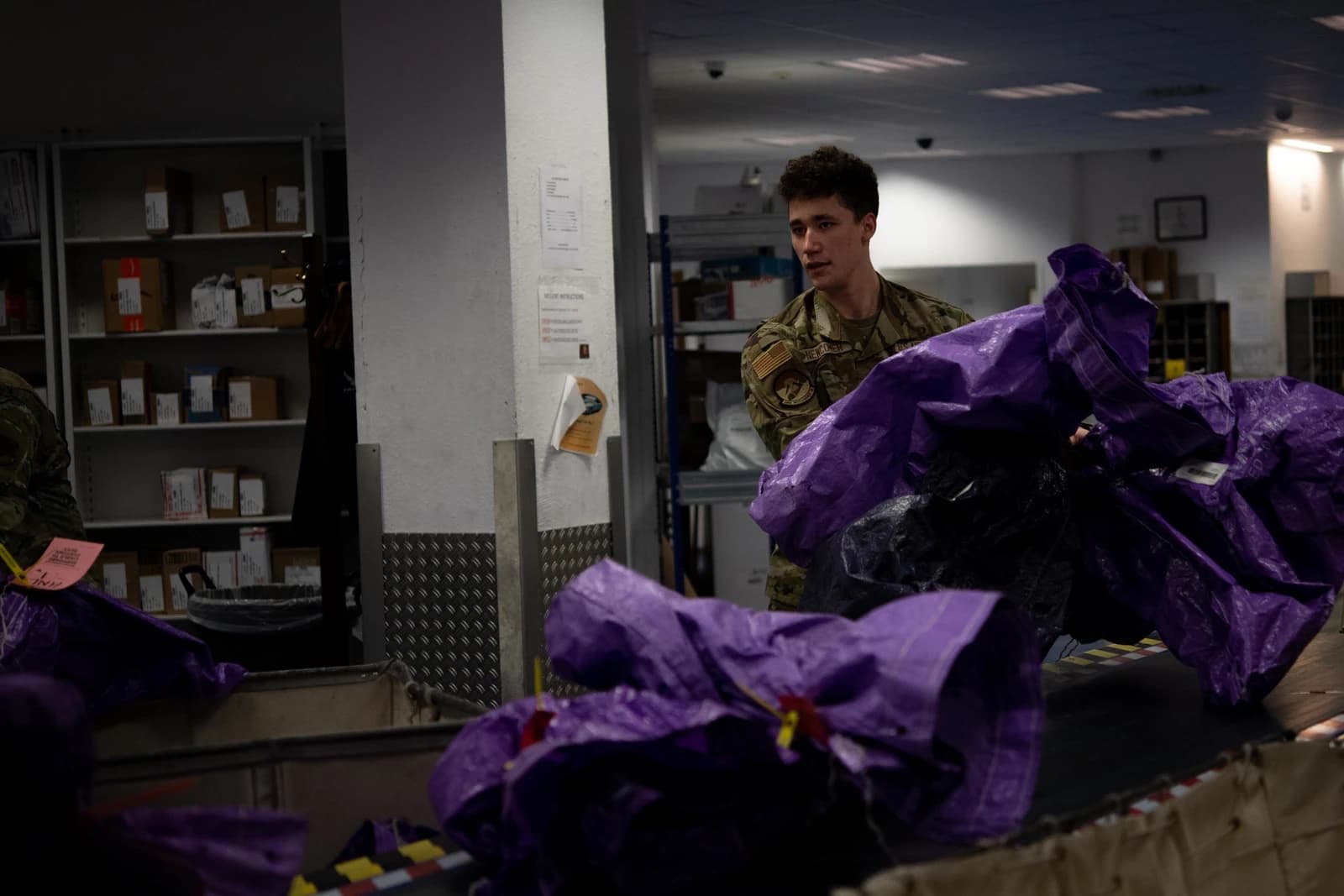 An NSPO postal employee sorts mail and packages in a facility.
