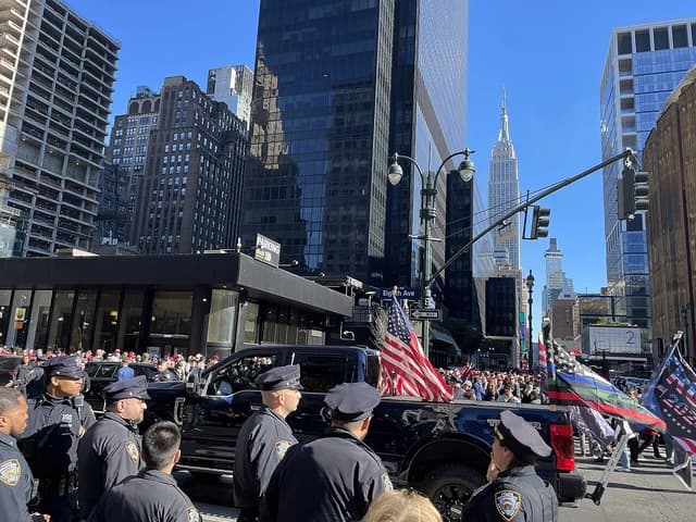 NYPD officers standing near a pro-Trump pickup truck with flags at a rally.