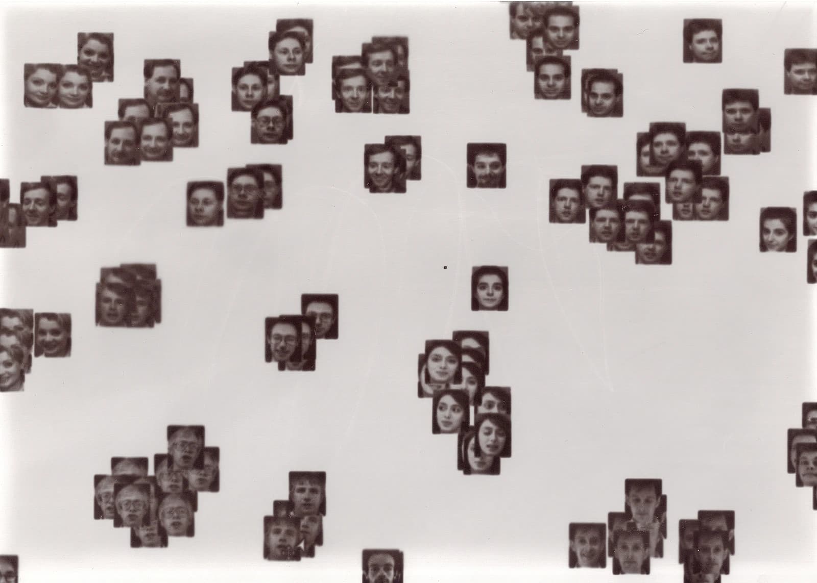 Many small, square black and white human faces scattered across a white background.