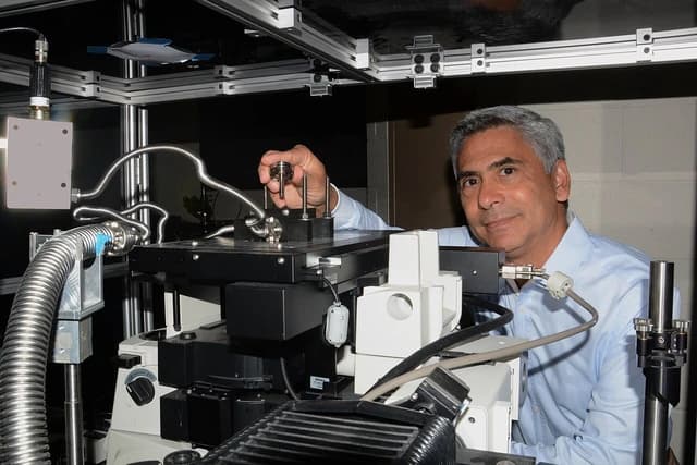 A world-class AFRL researcher looking at the camera while working with scientific equipment.