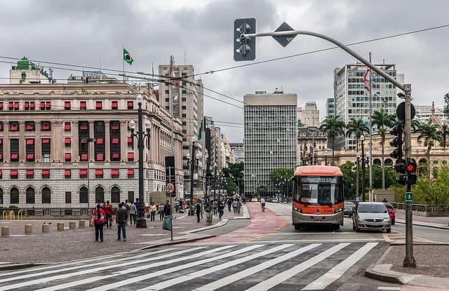 Public bus at an intersection in downtown Sao Paulo with people walking on sidewalks.