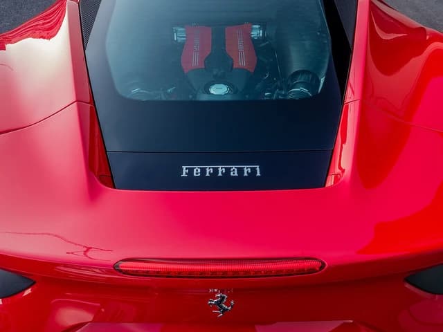 Rear view of a red Ferrari sports car in Monaco, showing the visible engine.