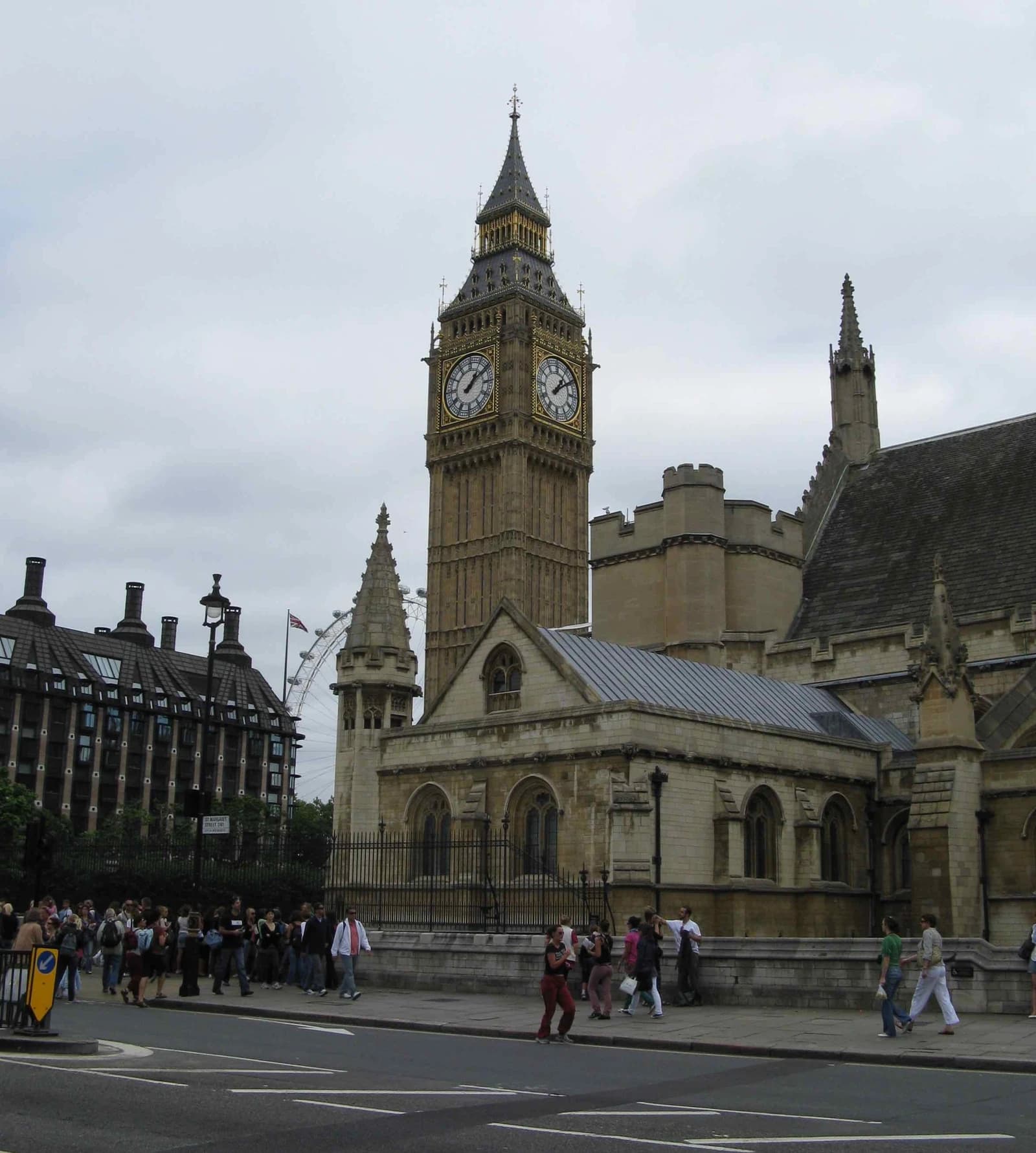 Elizabeth Tower of the Palace of Westminster with people walking on the street.