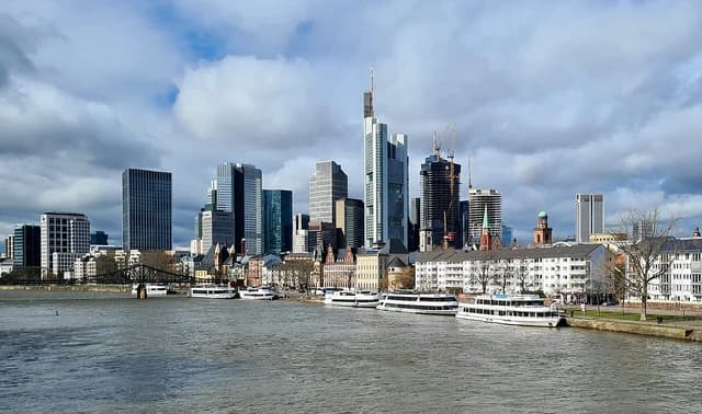 Frankfurt skyline along Main river with modern high-rise buildings and boats.