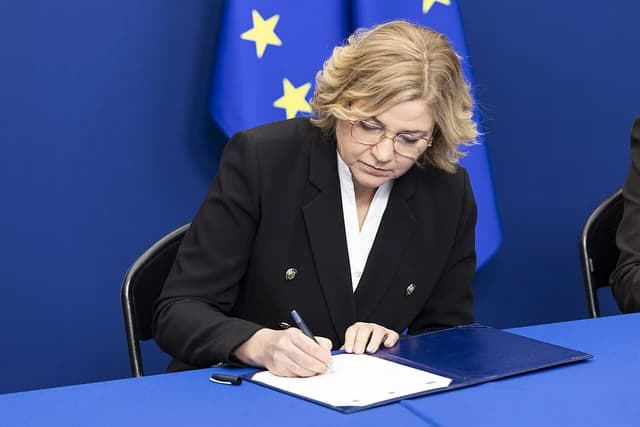 Henna Virkkunen, European politician, signing documents at a press briefing.