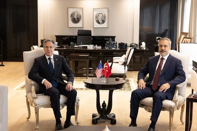 Secretary Blinken and Turkish Foreign Minister sit across from each other at a meeting.