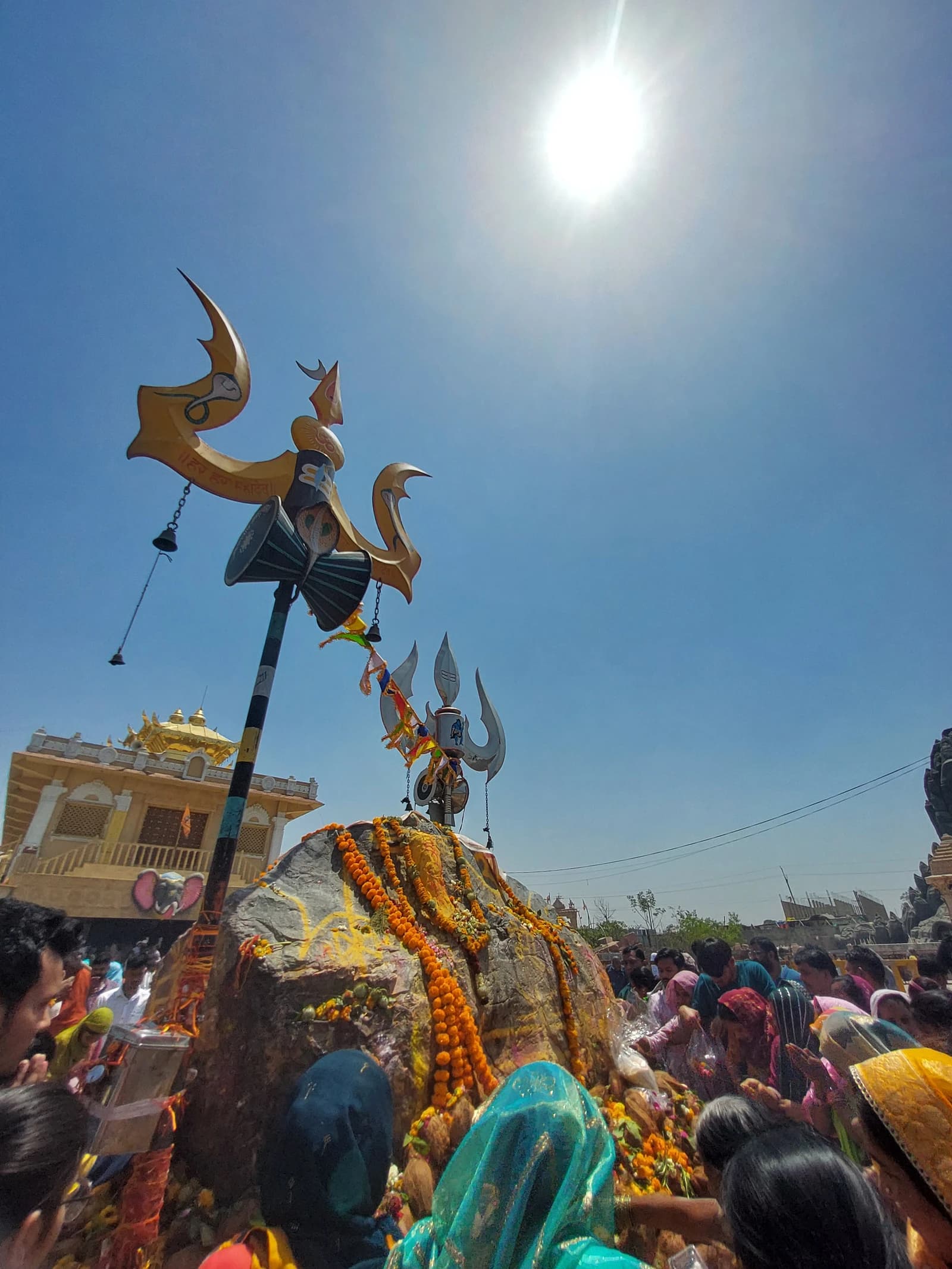 Devotees pray at a Shiva shrine adorned with trishuls and marigold garlands.