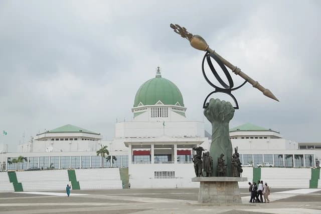 Exterior of the National Assembly Building in Abuja, Nigeria, under cloudy skies.