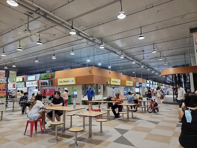 Diners eating at tables in the interior of Woodleigh Village Hawker Centre.