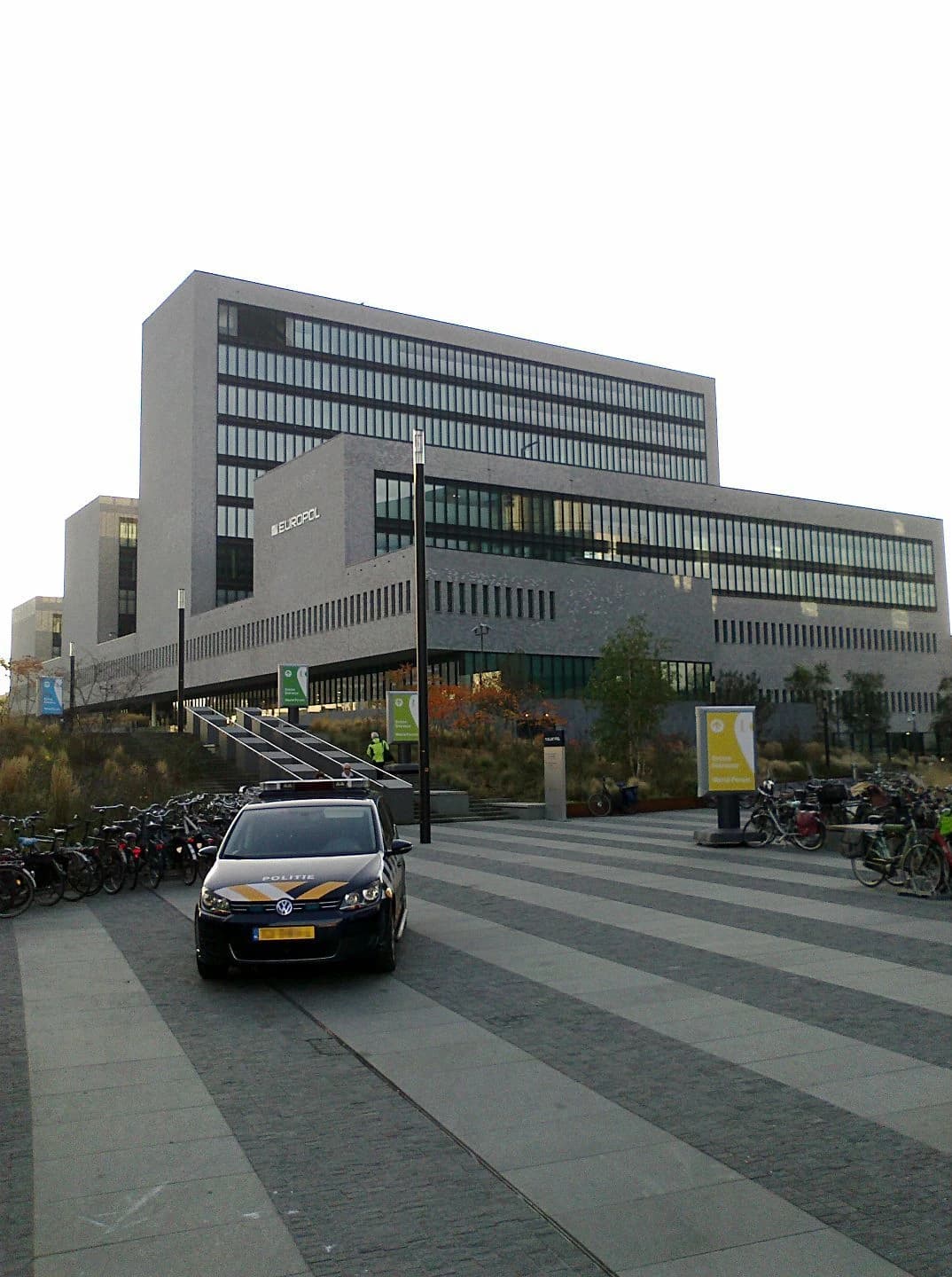 Europol headquarters building in The Hague, Netherlands, with a police vehicle.