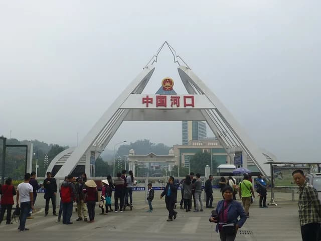 People walk under a large archway at the Hekou border crossing in China.