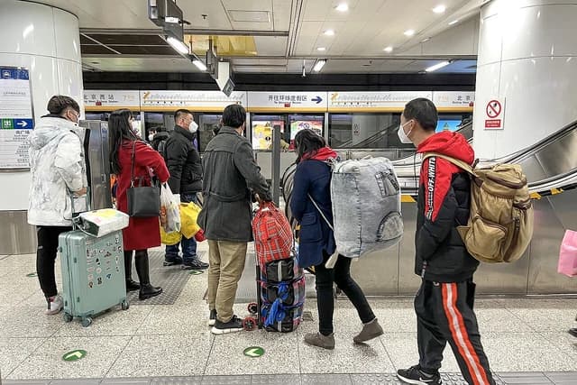 Travelers with luggage wait on a subway platform at Beijing West Railway Station.