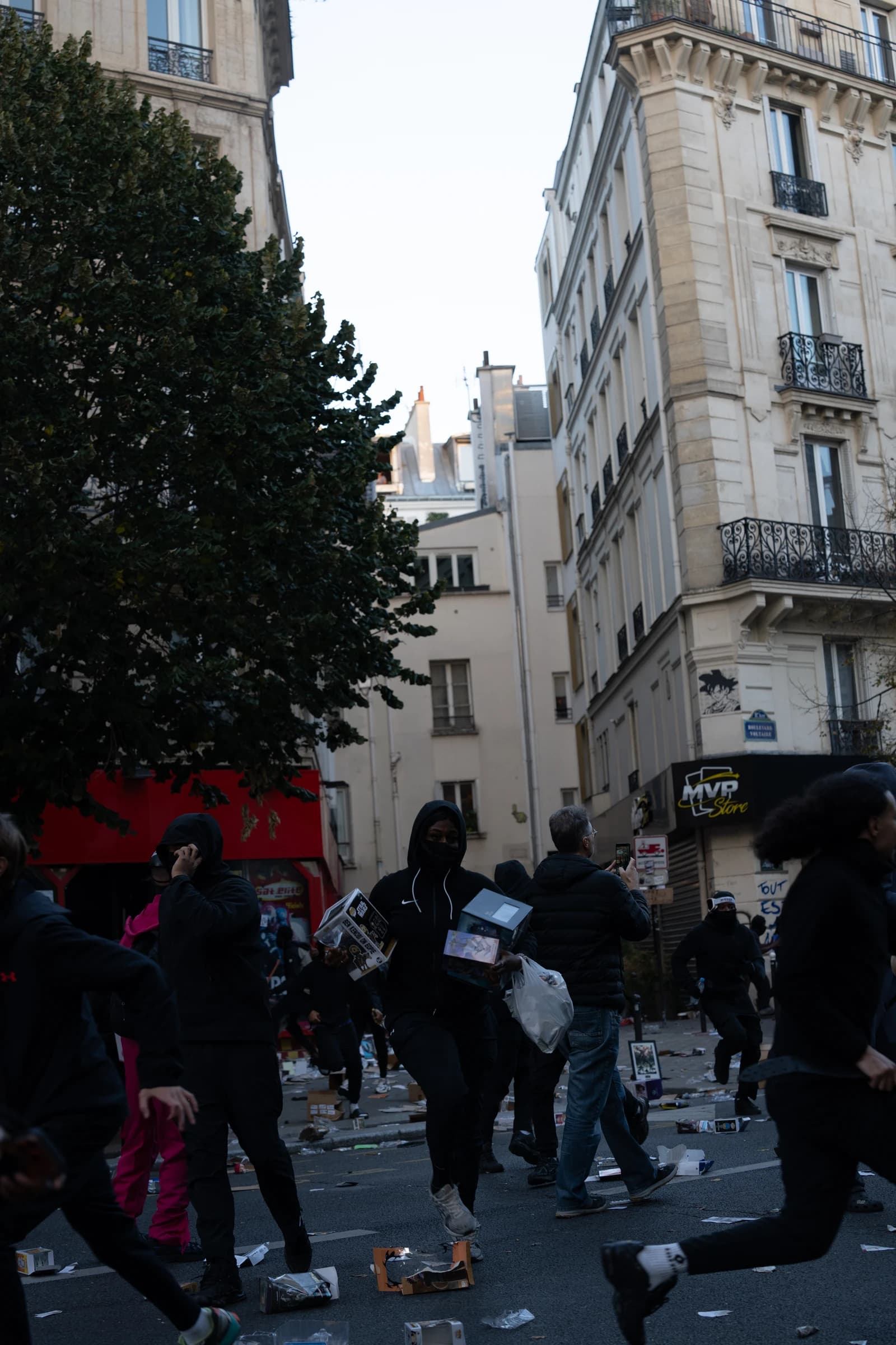 People running and walking on a street littered with debris in Paris.