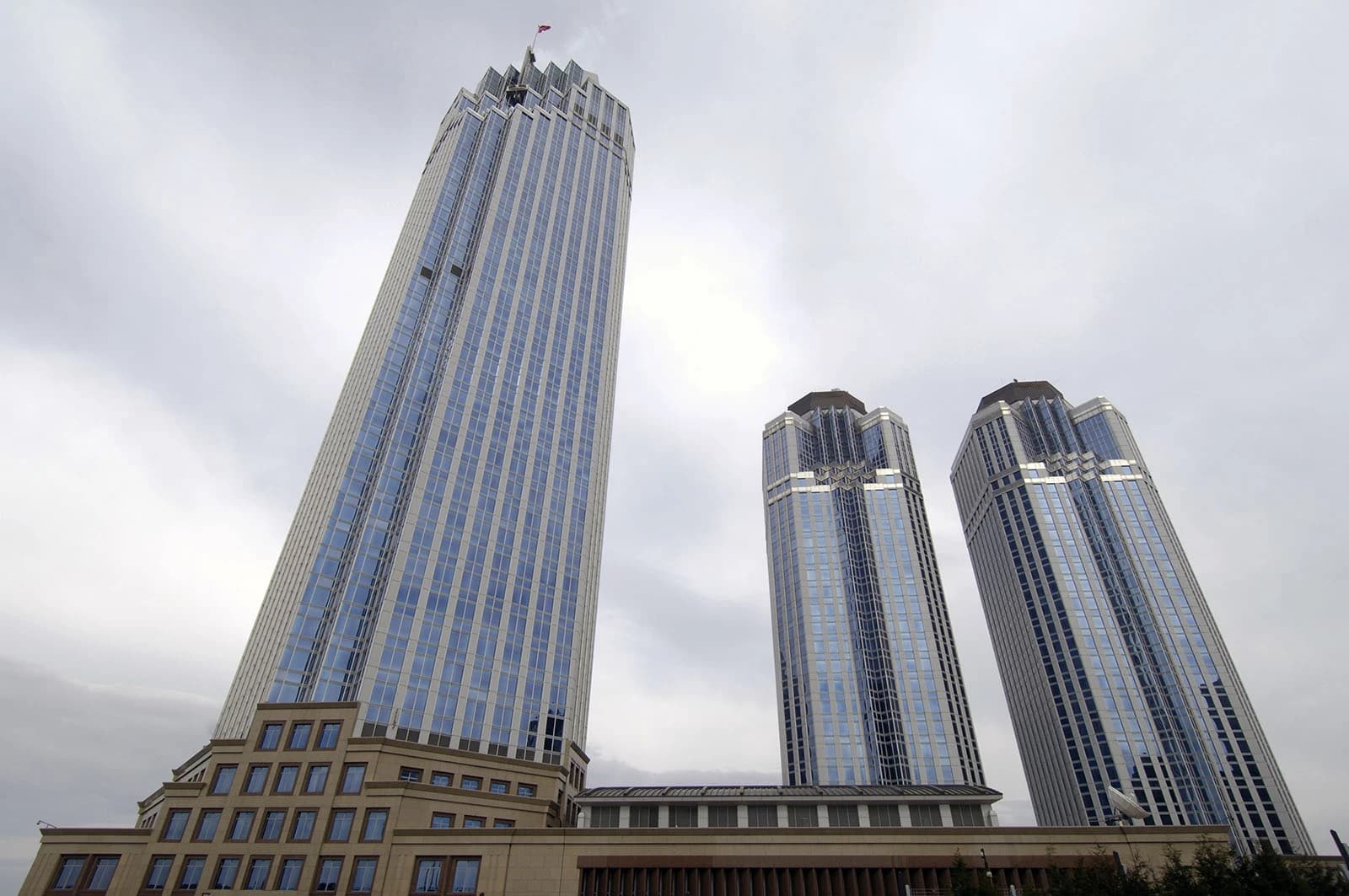 Three tall, glass-fronted buildings of İşbank headquarters in Istanbul, Turkey, under a cloudy sky.