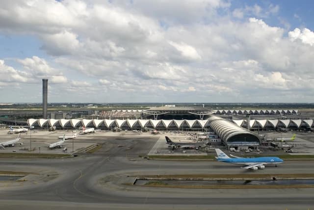 Aerial view of Suvarnabhumi International Airport with planes on the tarmac and a control tower.