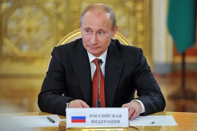 Vladimir Putin, Russian President, sitting at a conference table with a nameplate.