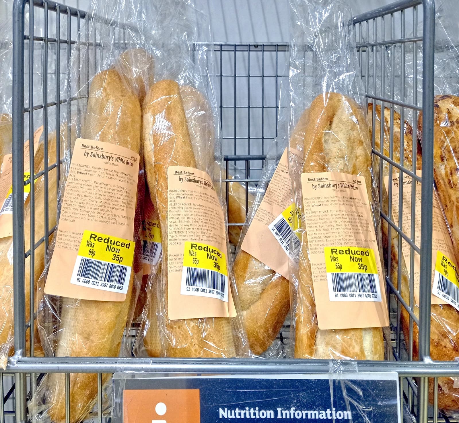 Baguettes with yellow 'Reduced' stickers from Sainsbury's private label in a supermarket.
