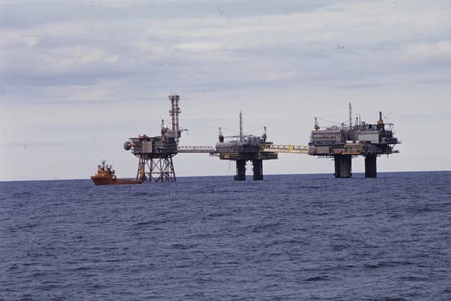 Several oil platforms connected by bridges with a supply vessel nearby in the North Sea.
