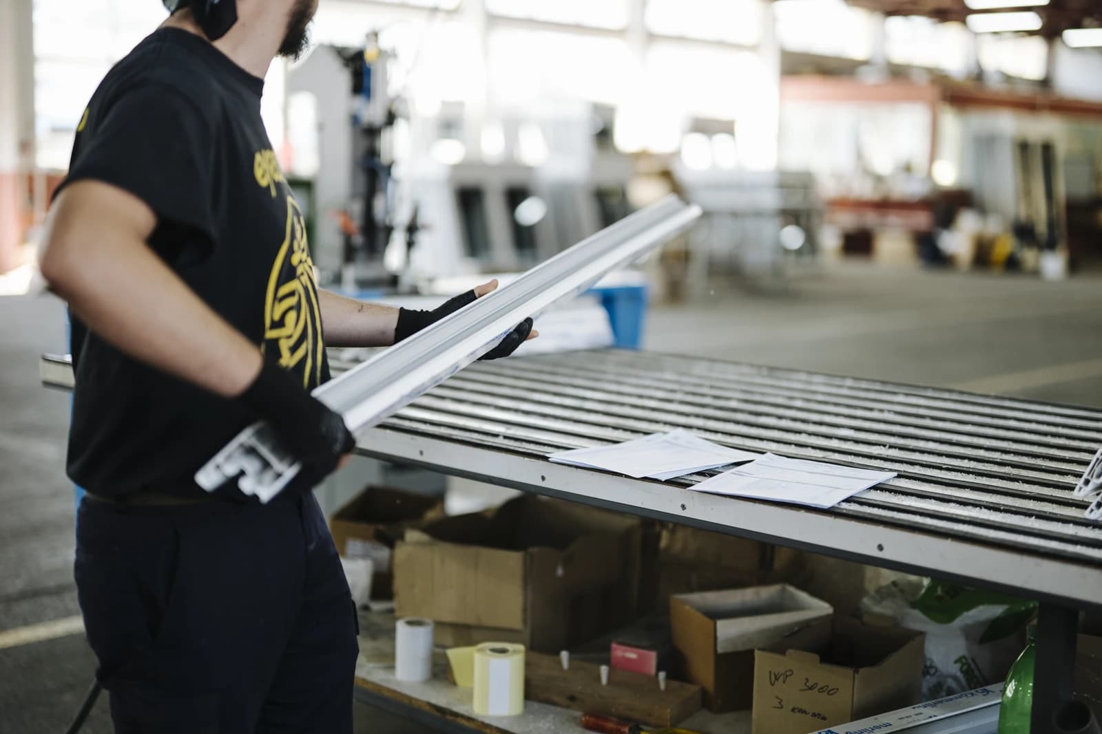 Worker in a warehouse holds metal parts.