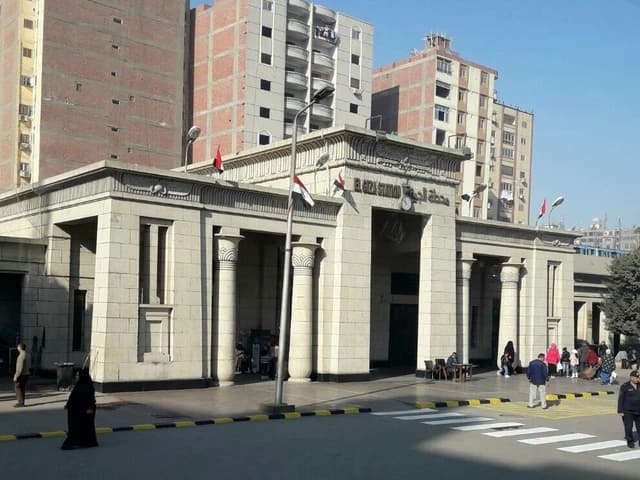 Exterior of El Giza Railway Station with architectural details and people walking outside.