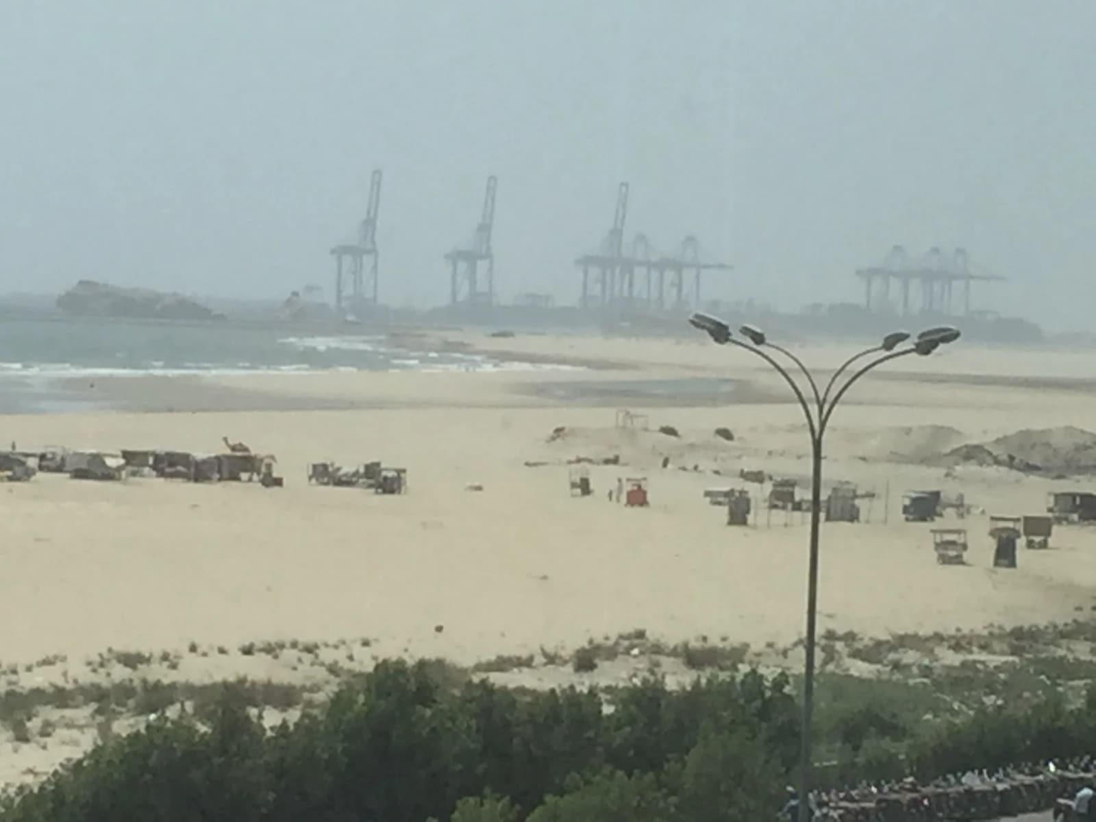 Cranes at Gwadar Port visible from Gwadar Beach in Pakistan.