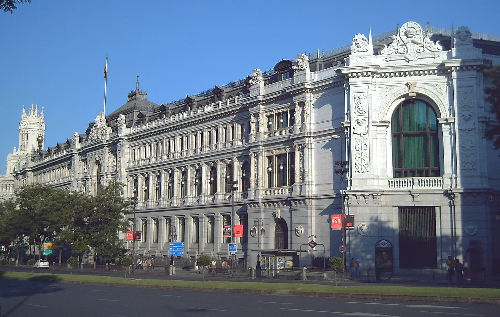 Exterior view of the Banco de España building with people and street in front.