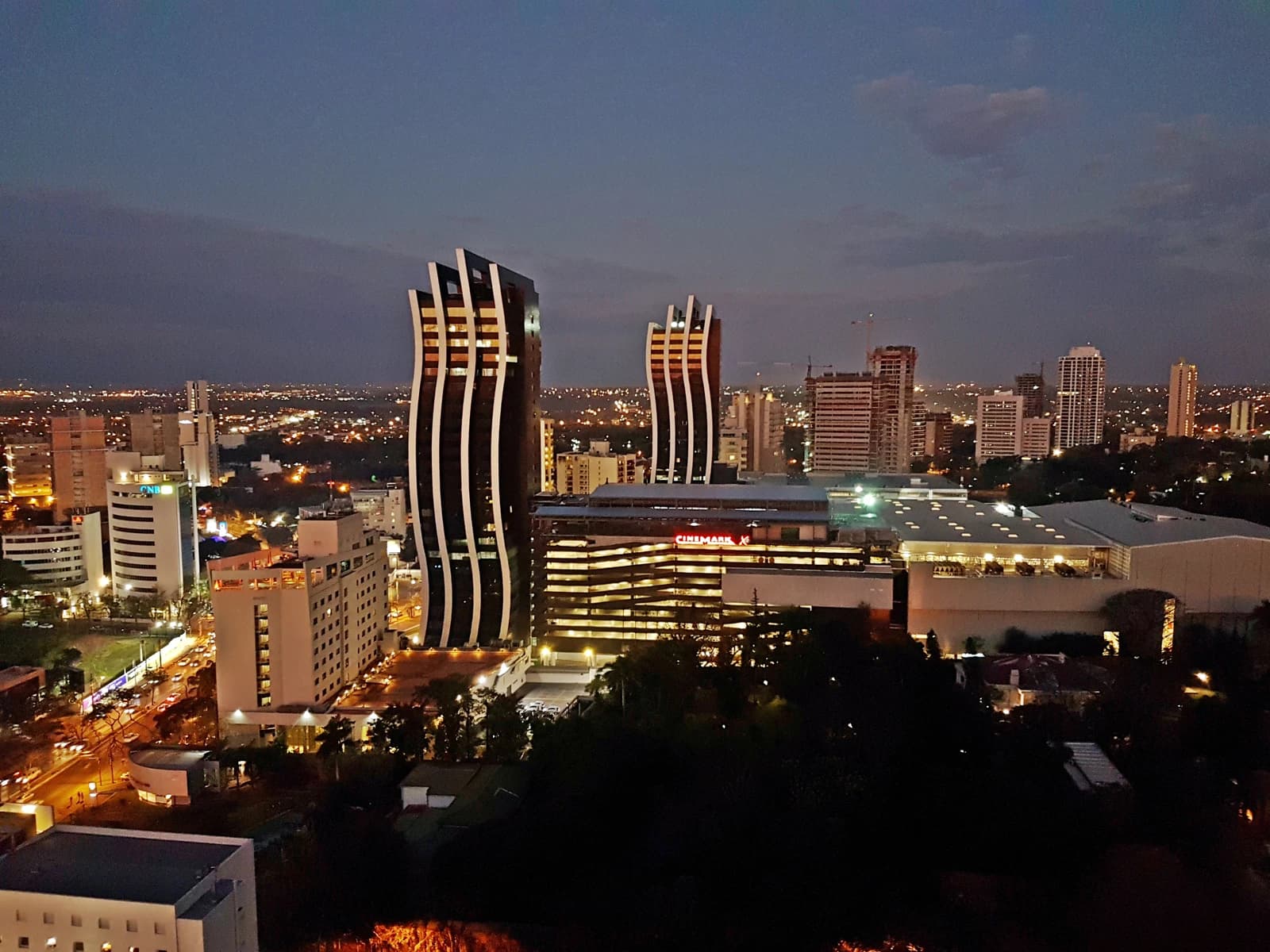 Evening cityscape of Asunción, Paraguay, showing several illuminated high-rise buildings.