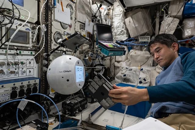 JAXA astronaut Takuya Onishi interacts with the CIMON AI robotic assistant inside a spacecraft.